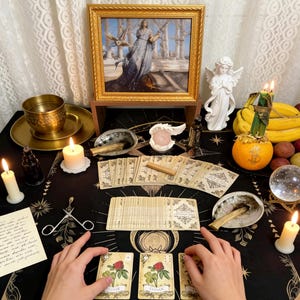 May include: A mystical scene with a black tablecloth adorned with celestial patterns. The table features tarot cards, candles, a framed painting, and a crystal ball. Two hands are holding tarot cards with a clover design.