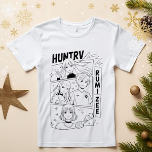 Puede incluir: Camiseta blanca con un gráfico en blanco y negro estilo manga. El diseño incluye los textos "HUNTRV" y "RUMINEE", junto con ilustraciones de cuatro personajes de anime en un diseño de cómic.
