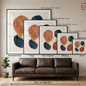 May include: A display of framed abstract art prints in various sizes, including 180 x 180 cm (70.9" x 70.9"), 120 x 120 cm (47.2" x 47.2"), 100 x 100 cm (39.4" x 39.4"), 70 x 70 cm (27.6" x 27.6"), and 50 x 50 cm (19.7" x 19.7"). The art features orange, blue, and gold shapes.