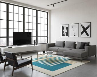 May include: Modern living room with a gray sectional sofa, two black armchairs, and a round coffee table. A large window and three framed abstract art pieces are visible. A blue and white geometric rug adds a pop of color.