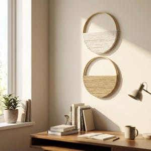 May include: Two circular wall baskets with a woven design. The top basket is white, and the bottom basket is tan. Both have a gold-colored, semi-circular handle. The baskets are hanging on a light-colored wall.