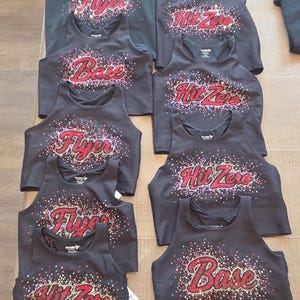May include: A collection of black sleeveless crop tops featuring rhinestone embellishments. The designs include the words Flyer, Base, and Hit Zero in red lettering, surrounded by a scattered pattern of red, white, and silver rhinestones.