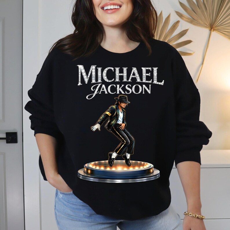 May include: Black sweatshirt featuring the text "MICHAEL JACKSON" in white, with a stylized image of Michael Jackson in a black suit and hat. The image shows Jackson performing on a stage with lights.