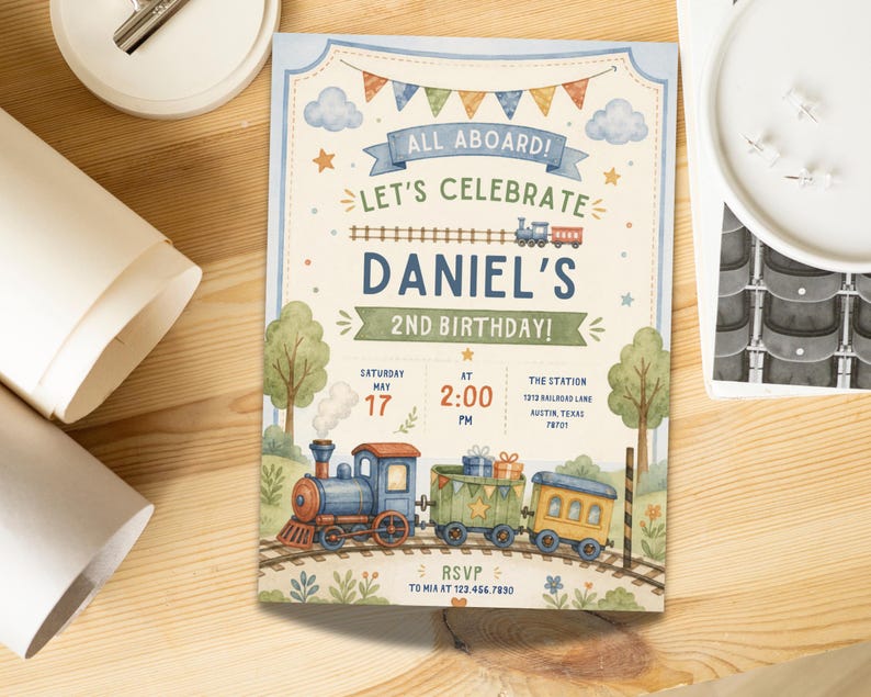May include: A rectangular birthday invitation card featuring a watercolor train theme. The text reads ALL ABOARD! LET'S CELEBRATE DANIEL'S 2ND BIRTHDAY! SATURDAY MAY 17 AT 2:00 PM THE STATION 1213 RAILROAD LANE AUSTIN, TEXAS 78701 RSVP TO MIA AT 123.456.7890.