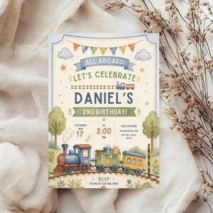 May include: A rectangular birthday invitation card featuring a watercolor train theme. The text reads: ALL ABOARD! LET'S CELEBRATE DANIEL'S 2ND BIRTHDAY! SATURDAY MAY 17 AT 2:00 PM THE STATION 1213 RAILROAD LANE AUSTIN, TEXAS 78731 RSVP TO MIA AT 123.456.7890.
