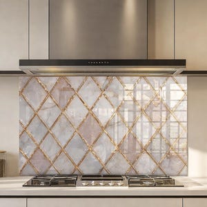 Puede incluir: Un protector contra salpicaduras de cocina con un patrón similar al mármol en blanco y gris, acentuado con líneas doradas en forma de diamante. El protector contra salpicaduras está instalado detrás de una placa de gas y debajo de una campana extractora de acero inoxidable.