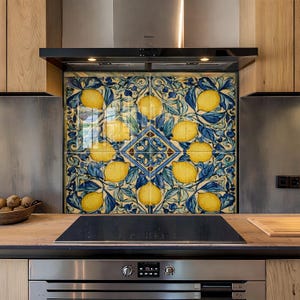 May include: A decorative kitchen backsplash featuring a repeating pattern of yellow lemons and blue leaves. The design is centered with a diamond-shaped pattern. The backsplash is installed above a black stovetop and stainless steel oven.