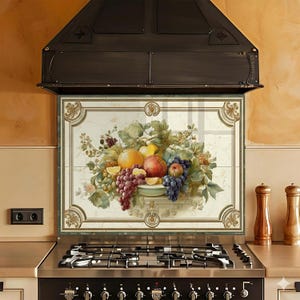 May include: A decorative kitchen backsplash featuring a still life of fruit. The artwork includes oranges, grapes, peaches, and lemons. The backsplash is framed with a green and gold border, and is installed above a stainless steel stove.