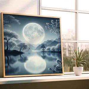 May include: A framed print of a serene landscape featuring a large full moon reflected in a lake. The artwork depicts snow-covered trees, mountains, and a tranquil atmosphere. The frame is a light wood color, and the overall color palette is cool blues and whites.
