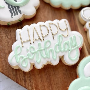 May include: A collection of decorated sugar cookies with a green and gold color scheme. The cookies feature the words 'Sweet 16', 'Happy Birthday', 'McKenzie', and the number '16' with a tire tread design. There are also cookies shaped like a car and a key with a tassel.