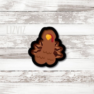 May include: A brown turkey cookie cutter with a red wattle and yellow beak. The turkey is facing right and has a detailed design of feathers.