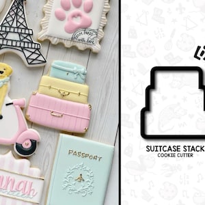 May include: A set of cookie cutters in the shape of a stack of suitcases. The cookie cutters are black and are on a white background with a pattern of various shapes and designs. The text "SUITCASE STACK COOKIE CUTTER" is below the cookie cutters.