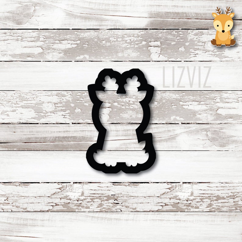 May include: Black cookie cutter shaped like a deer with antlers. The cutter's outline is detailed, ideal for making festive biscuits. The image is set against a white, weathered wood background.