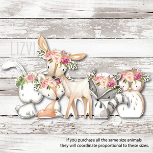 May include: Five watercolour woodland animal cutouts with floral crowns. The animals are a deer, a fox, a rabbit, a raccoon, and an owl. The cutouts are on a white wood background.