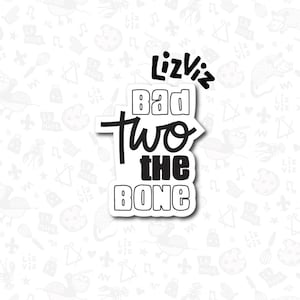 May include: Black and white sticker with the text "LizViz Bad two the bone" in a handwritten style.