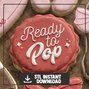 May include: A red cookie with white icing that reads "Ready to Pop." The cookie has a scalloped edge and is surrounded by other cookies. Below the cookie is a black rectangle with the text "STL INSTANT DOWNLOAD."