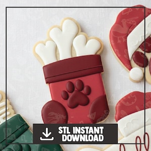Puede incluir: Una galleta decorada con forma de calcetín burdeos con una huella de pata y galletas con forma de hueso. La imagen incluye el texto "STL INSTANT DOWNLOAD" en un recuadro negro.