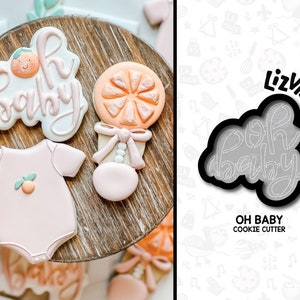 Peut inclure: Un ensemble de trois emportes-pi&egrave;ces en forme de body b&eacute;b&eacute;, d'un hochet et des mots "Oh Baby". Les emportes-pi&egrave;ces sont noirs et ont un contour blanc. Le texte "Oh Baby Cookie Cutter" est imprim&eacute; sous les emportes-pi&egrave;ces.
