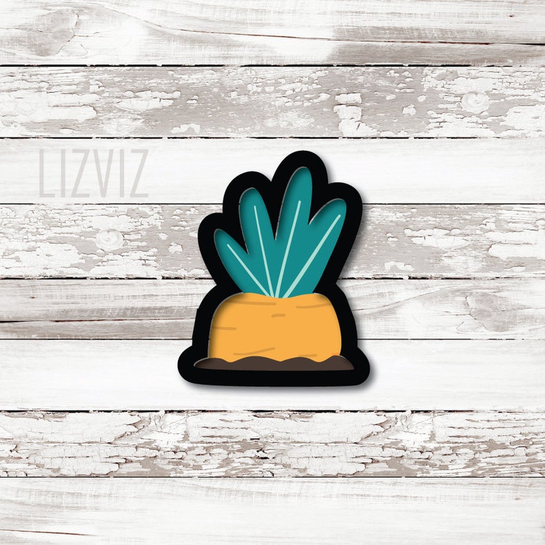May include: A black cookie cutter shaped like a carrot with green leaves. The carrot is orange and the leaves are teal.