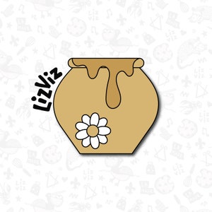 May include: A brown ceramic honey pot with a white daisy on the side. The pot is filled with honey and has a drip of honey coming out of the top.