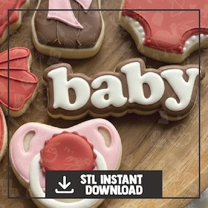 May include: Assortment of baby-themed cookies on a wooden surface. The cookies include a pacifier, a diaper, and the word "baby" in white icing on a brown cookie. The pacifier is pink with a red center. The image also includes the text "STL INSTANT DOWNLOAD".
