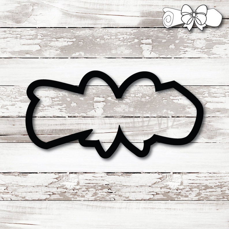 May include: Black cookie cutter in the shape of a scroll with a bow. The cutter is on a white, distressed wood background. A smaller scroll with a bow is in the upper right corner.
