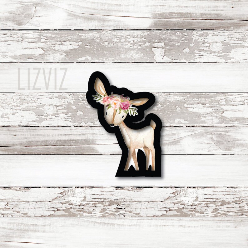 May include: A black and white cookie cutter in the shape of a deer with a floral crown. The deer is standing on all four legs and has a long neck. The floral crown is made of pink and white flowers.