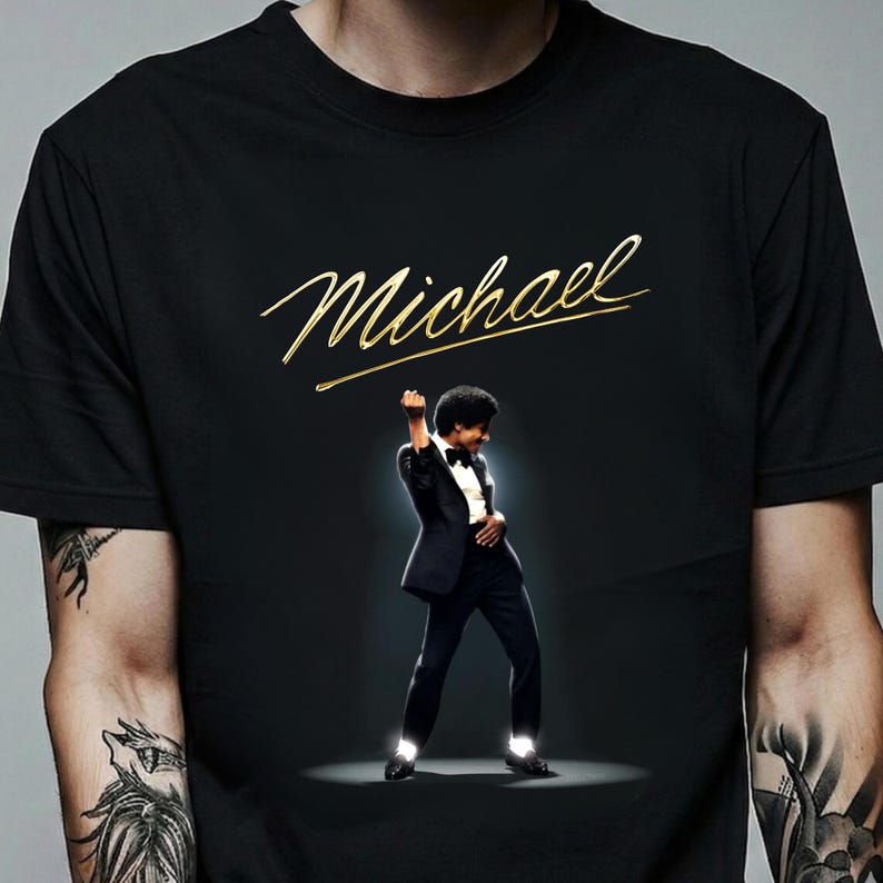 May include: Black t-shirt with the gold script name "Michael" above an image of a man in a black tuxedo, striking a pose. The image is set against a dark background, with a spotlight effect.
