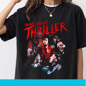 May include: Black t-shirt with the words "Michael Jackson's Thriller" in red, and a graphic of Michael Jackson surrounded by zombies. The design is a vintage-style print.