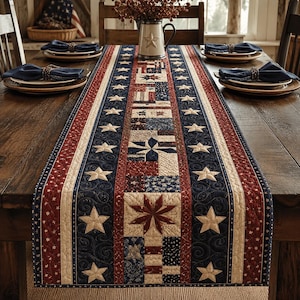 Puede incluir: Un camino de mesa patriótico con un diseño acolchado en colores rojo, blanco y azul. El camino de mesa tiene un patrón de estrellas y rayas, con una sección central de cuadrados de patchwork y estrellas bordadas.