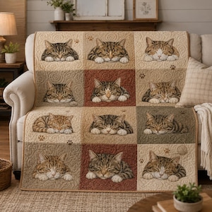 May include: A quilted sofa cover featuring a repeating pattern of sleeping tabby cats in various squares. The squares are in shades of beige, brown, and green. Paw prints and a ball of yarn are also included in the design. The cover is draped over a beige sofa.