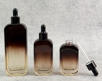 May include: Three brown glass dropper bottles of different sizes. The bottles have a gradient effect, going from dark brown at the top to a lighter amber shade at the bottom. One bottle has a dropper, and the other two have black caps.
