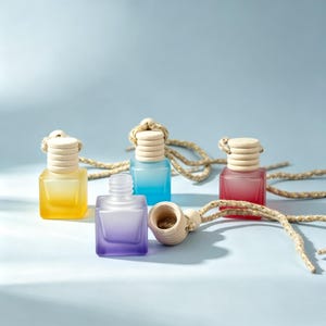 May include: Four square glass bottles with a frosted gradient finish in yellow, blue, red, and purple. Each bottle features a light-colored wooden screw-top cap attached to a braided beige hanging cord. One bottle is shown with its cap removed.