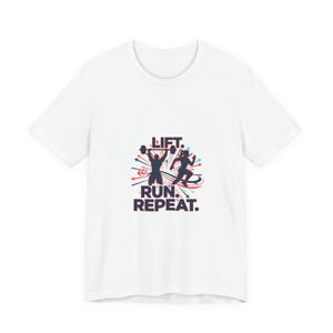 Puede incluir: Camiseta blanca con un diseño gráfico que presenta dos siluetas: una levantando una barra y otra corriendo. El texto "LIFT. RUN. REPEAT." está impreso en negrita, con acentos rojos, azules y negros.