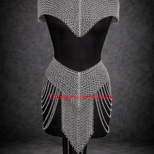 Pu&ograve; includere: Un indumento in cotta di maglia argentata composto da una parte per le spalle a maniche corte e una parte per la vita abbinata con frange di catene pendenti. Le maglie metalliche formano uno scollo a V. Il testo UniqueArmoryLtd &egrave; visibile.