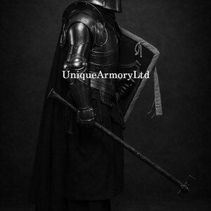 K&ouml;nnte beinhalten: Schwarz-Wei&szlig;-Bild einer vollst&auml;ndigen mittelalterlichen R&uuml;stung. Die R&uuml;stung umfasst einen Helm, Schulterpanzer, Brustplatte sowie Arm- und Beinschutz. Ein langer schwarzer Umhang und eine Waffe sind ebenfalls zu sehen. Der Text "UniqueArmoryLtd" ist auf dem Bild aufgedruckt.