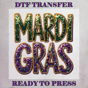 Peut inclure: Transfert DTF avec les mots "MARDI GRAS" en grandes lettres à paillettes. Les lettres sont soulignées en or et remplies de paillettes vertes et violettes. Le texte "READY TO PRESS" est en dessous.