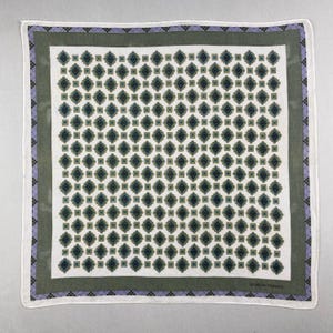 Peut inclure: Foulard carré blanc avec un motif géométrique répété dans les tons de vert et de bleu. La bordure présente un cadre vert, une bande lavande avec un motif de losanges et un bord blanc. Le nom de la marque est imprimé en bas à droite.