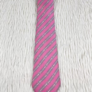 May include: A necktie featuring a vibrant pink base color with a repeating pattern of diagonal silver-grey stripes. Each stripe contains a series of interconnected oval chain-link motifs in white and grey, creating a structured, geometric design.
