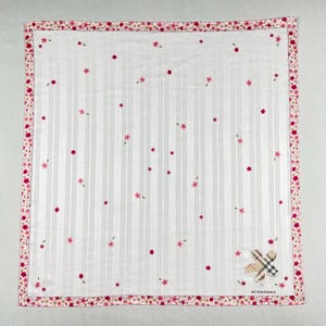 May include: White square handkerchief with vertical stripes and scattered pink floral embroidery. A pink floral border frames the edges. A Burberry logo patch is in the corner.