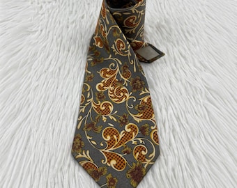 May include: A necktie featuring a dark gray base color with an intricate pattern of swirling gold and brown floral motifs. The design includes small houndstooth textures within the shapes, creating a detailed visual contrast across the fabric.