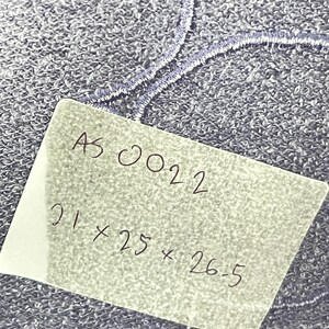 Może przedstawiać: Zbliżenie na teksturowaną, niebieską tkaninę z haftowanymi detalami. Ręcznie napisana etykieta wyświetla tekst "AS 0022" oraz wymiary 21 x 25 x 26,5.