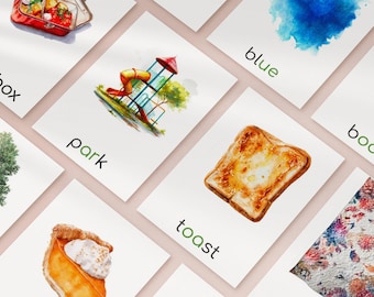 May include: A collection of watercolor flashcards featuring illustrations and words. Cards include a playground, toast, and the word "park". The cards are arranged on a light pink surface.