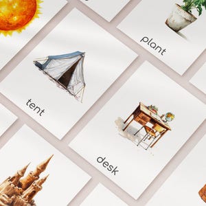 May include: Watercolor flashcards with illustrations of a sun, tent, desk, plant, and other objects. Each card has the object's name printed below the image. The cards are arranged on a white surface.