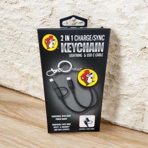 Könnte beinhalten: Schwarz-gelbes 2-in-1-Lade-/Sync-Schlüsselanhänger mit Lightning- und USB-C-Kabel. Die Verpackung zeigt ein Cartoon-Biber-Logo und den Text "2 IN 1 CHARGE/SYNC KEYCHAIN". Kompatibel mit den meisten Powerbanks und Apple- und Android-Geräten.