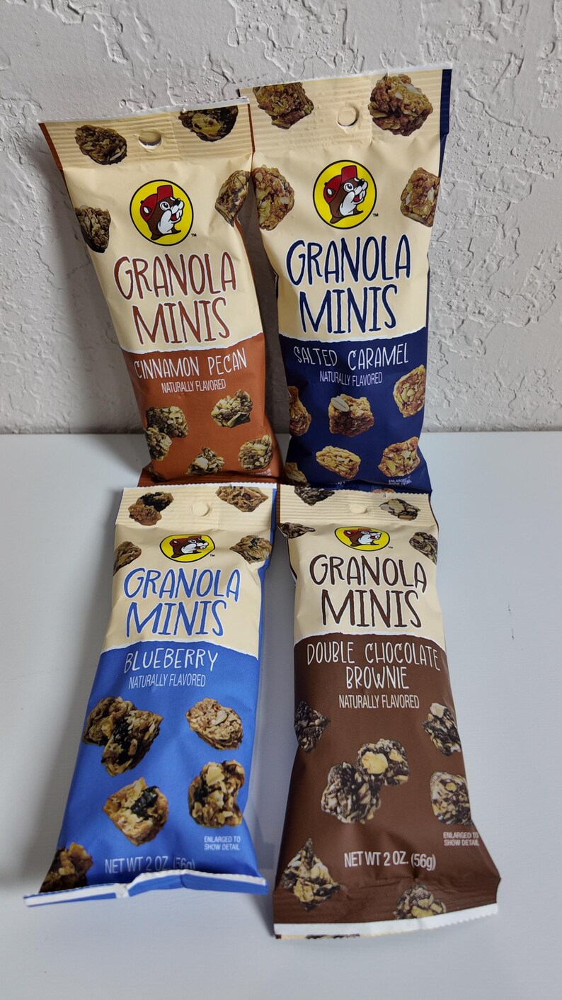 May include: Four bags of Granola Minis in Cinnamon Pecan, Salted Caramel, Blueberry, and Double Chocolate Brownie flavors. Each bag features a cartoon beaver logo and the words "Granola Minis". The bags are 2 oz (56g) each.