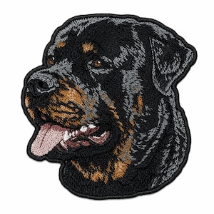 May include: An embroidered patch featuring the head of a Rottweiler dog. The design showcases the dog's black and tan fur, brown eyes, and a pink tongue hanging out of its mouth. The patch has a black stitched border and detailed thread work.