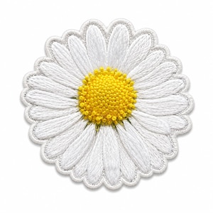 Puede incluir: Un parche bordado circular con un diseño de flor de margarita. El centro consiste en un disco amarillo texturizado y elevado que representa la cabeza de la flor, rodeado por numerosos pétalos blancos con detalles de costura visibles y un borde blanco.