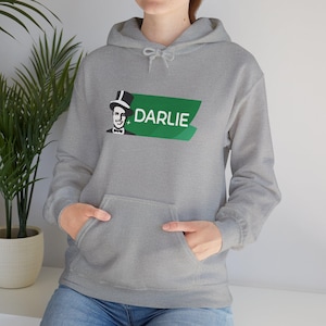 May include: A gray hoodie with a front pocket and a drawstring hood. The hoodie features a green banner with the word "DARLIE" in white text and a black and white graphic of a man in a top hat.