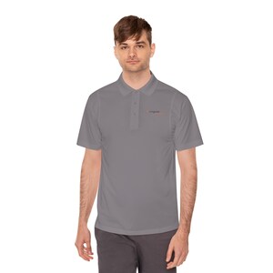 May include: A gray polo shirt with short sleeves and a collared neckline. The shirt has a three-button placket and a small logo on the chest. The person in the image is wearing gray pants.